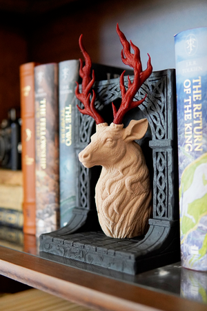 Decorative deer head bookend on a shelf with books and a candle.