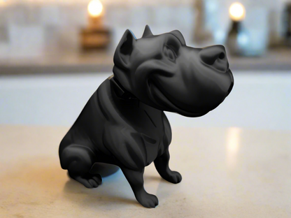 A black dog sculpture with a cartoon style, displayed on a flat surface, likely made from resin or a similar material.